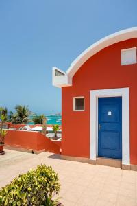 达喀尔拉马德拉戈 - 冲浪海滩碧海酒店的一座红色的建筑,有蓝色的门和大海