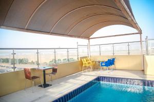 吉达Areen Hotel Al Basateen的一个带椅子和桌子的游泳池以及一张桌子