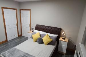 安特里姆Millhouse Cottage A Luxury 3 bed Bungalow的一间卧室配有一张黄色和灰色枕头的床