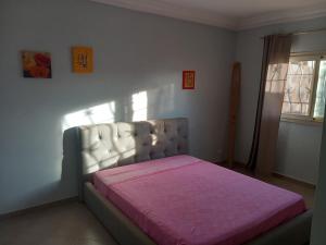 NdéyaneCasa Kassi的一间卧室配有一张床铺,床上铺有粉色毯子