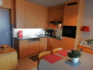 奥斯坦德De Strandwandeling 0203 Appartement met frontaal zeezicht的厨房配有木制橱柜和一张带红色桌布的桌子。