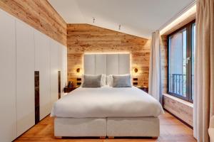夏蒙尼-勃朗峰格兰德酒店的卧室设有白色的床和木墙