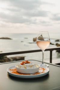 比亚里茨Hôtel de La Plage的桌上的一小盘食物和一杯葡萄酒