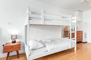 伦敦1 BR Flat Piccadilly Sleep 7 in London VR10的卧室配有白色双层床和木桌