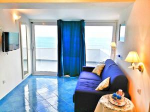 阿马尔菲Casa Vacanze La Rosa Del Mare的客厅设有蓝色的沙发和大窗户