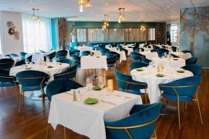 罗什福尔Hôtel & Restaurant des Remparts的用餐室配有白色的桌子和蓝色的椅子