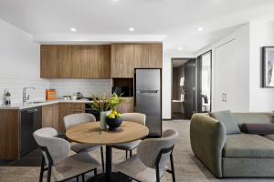 吉朗Quest Geelong Central的厨房以及带桌椅的起居室。