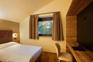 瓦尔格里森凯Valgrisa Mountain Lodges 1的一间卧室配有一张床和一个带椅子的窗户
