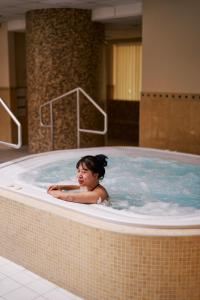 科沃布热格Jantar Hotel & SPA by Zdrojowa的女人坐在热水浴缸里