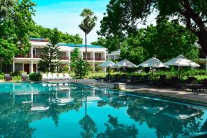 亭可马里Anantamaa Hotel的度假村前方的游泳池,种植了树木和遮阳伞