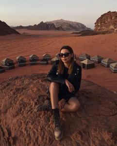 瓦迪拉姆Star World Camp的坐在沙漠岩石上的女人