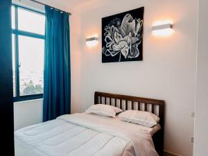 达累斯萨拉姆Elles Residence的一间卧室配有一张带蓝色窗帘的床和一扇窗户