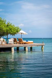 格兰德岛Hotel Coralina Island的水面上带椅子和遮阳伞的码头