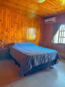 泰马斯德瓜维尤Cabañas Tacuabe的卧室配有木墙内的一张床