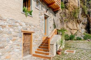 德尔维奥Green Chalet Scalotta - Nature Relax Lake View的石头房子,设有木门和楼梯
