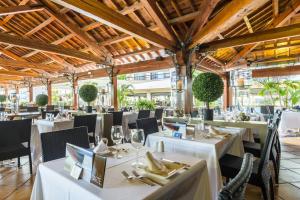 圣蓬萨扎菲洛洁美旅馆的餐厅设有白色的桌椅和木制天花板。