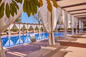 阿尔库迪亚港扎菲罗热带公寓的酒店游泳池配有白色遮阳伞