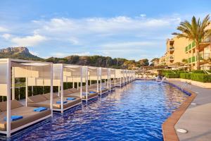 卡拉马奎达卡拉马奎达蓝宝石维瓦酒店的度假村的游泳池,里面设有床铺