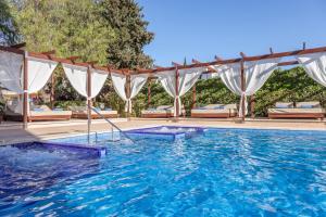 帕尔马诺瓦Zafiro Palmanova的拥有蓝色海水和白色窗帘的游泳池