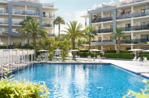 阿尔库迪亚港萨菲罗宫西拉斯酒店的大楼前的游泳池配有椅子和遮阳伞
