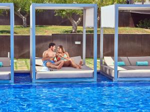 帕尔马诺瓦扎菲洛帕莱斯帕尔马诺瓦酒店的坐在游泳池旁床边的男人和女人