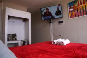 利马La Belle Vue的一间卧室配有一张红色的床和两张可移动的毛巾