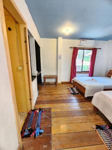 瓜隆岛Sweet Jungle Bungalows的一间卧室设有两张床,铺有木地板