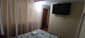 利马Aruba Suite Hotel的卧室配有一张床,墙上配有电视