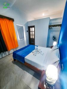 Ribeira GrandePousada Green Place的一间卧室配有一张大床,配有蓝色和橙色的窗帘