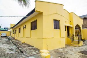 AgegeARO (1.0) 2BD Studio Flat (Abule-Egba/Lagos)的一座黄色的建筑,前面有一辆汽车