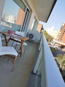 拉普拉塔Calmo Dooneo Appart La Plata - Departamentos con COCHERA的阳台配有木桌和椅子。