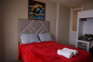 利马La Belle Vue的一间卧室配有红色的床和毛巾