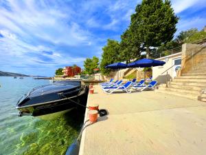 斯塔拉诺瓦利亚Villa Olivija-direkt am Strand!的停泊在码头旁的带椅子和遮阳伞的船只