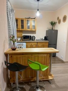 AizkraukleAizkraukles studio tipa dzīvoklis的厨房配有木台和2张绿色酒吧凳