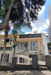 库里提巴Joshua Tree Hostel - Curitiba的建筑物前的树,有栅栏
