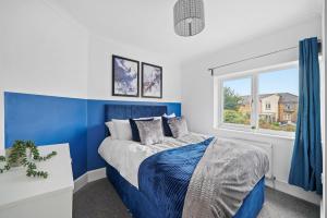 彼得伯勒3 bedrooms with parking ideal for long stays的蓝色和白色的卧室设有床和窗户
