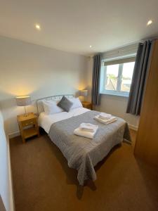 吉尔福德Blue Sky Apartments@ Abbots Yard, Guildford的一间卧室配有一张床,上面有两条毛巾