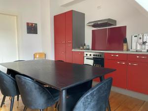 曼海姆Stadthaus Room 2 mit Hochbett for 3 Persons or Eltern mit 2 Kindern的厨房配有红色橱柜和黑色桌椅