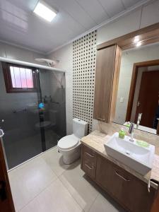 格拉玛多Casa mais Central de Gramado的浴室配有卫生间、盥洗盆和淋浴。
