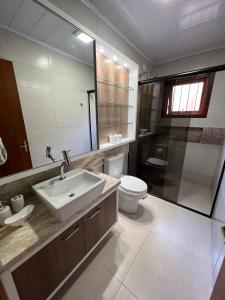 格拉玛多Casa mais Central de Gramado的一间带水槽、卫生间和镜子的浴室