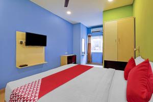 KāhārpāraOYO Flagship 81041 New Jebiis Inn的一间卧室配有一张带红色枕头的床和一台电视。