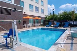 斯德伯克Hampton Inn & Suites Cedar Park North Austin, Tx的一座带椅子和遮阳伞的游泳池位于一座建筑旁边