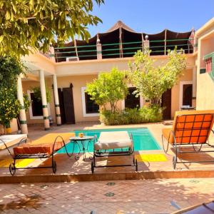 马拉喀什Riad Rime Garden Marrakech的房屋旁的游泳池配有桌椅