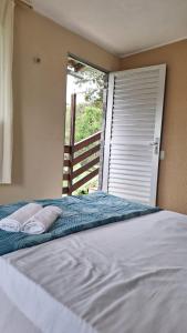 帕科蒂Pousada Rota Do Beija Flor PACOTI-CE的窗户前的一张带两个枕头的床