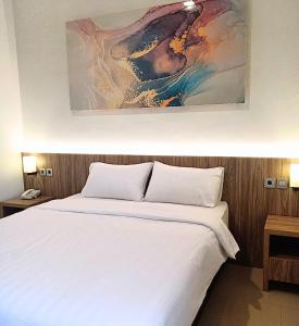 TjileungsirThe Safiina Point Syariah Hotel的卧室配有一张白色床,墙上挂有绘画作品