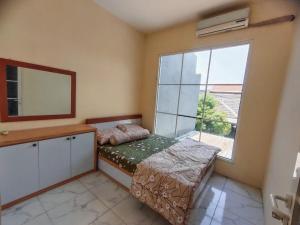 Mulia Homestay Pasuruan的一间卧室设有一张床和一个大窗户