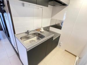 宜野湾市BiBi Hotel FUTENMA的厨房配有不锈钢水槽