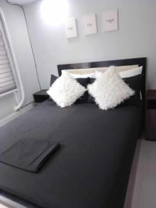 卡加盐德奥罗Aloha Hale One Oasis Cdo的一张黑色的床,上面有两个白色的枕头