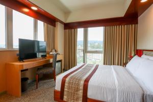 碧瑶Sotogrande Hotel Baguio的酒店客房配有一张床和一张书桌及一台电视