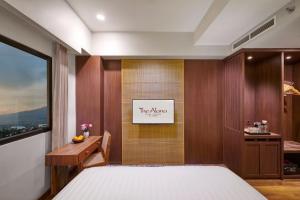 玛琅The Alana Hotel Malang的一间卧室配有一张床、一张书桌和一个窗户。